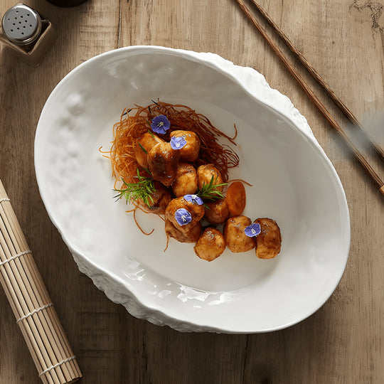 White oval ceramic dinner plate with textured rock design and curved edge – modern minimalist style for stylish meal presentation.