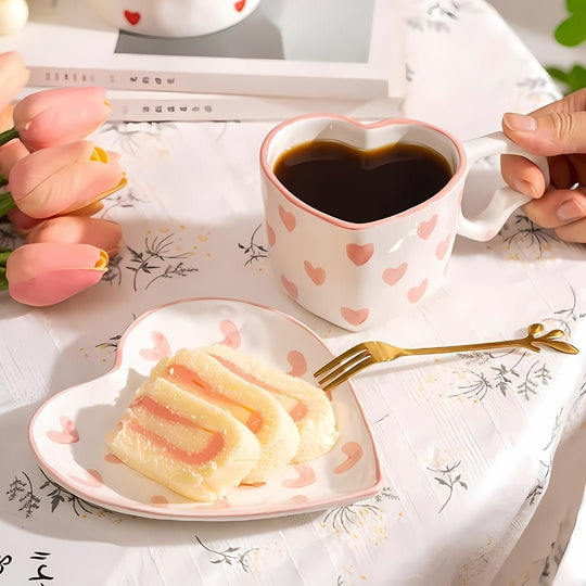 Romantic heart-shaped ceramic mug and matching dessert plate with pink heart prints, styled with coffee and cake — by European House Hold