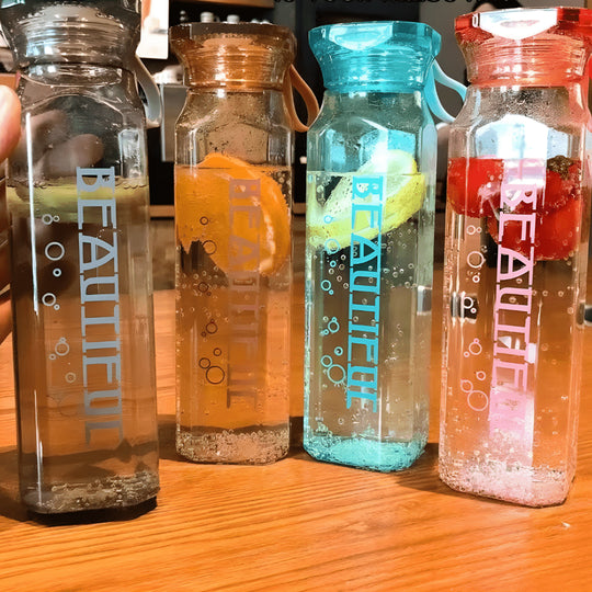 Diamond-shaped glass water bottle with fruit infusion, 500ml, available in amber, aqua, and ruby pink – eco-friendly with strap.