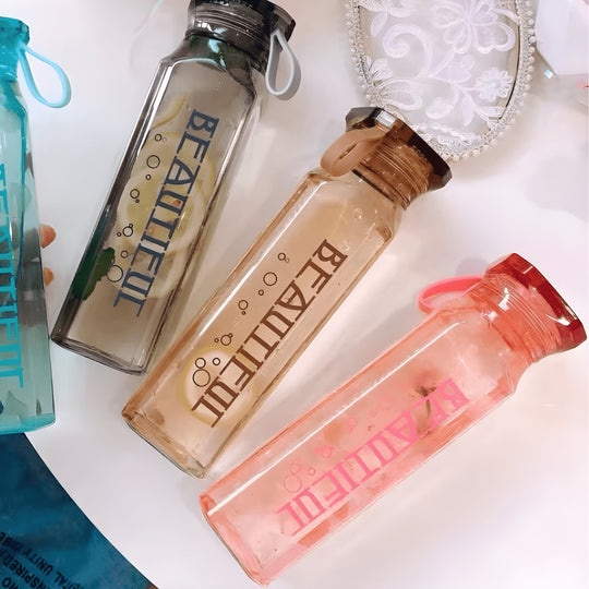 Diamond-shaped glass water bottle with fruit infusion, 500ml, available in amber, aqua, and ruby pink – eco-friendly with strap.