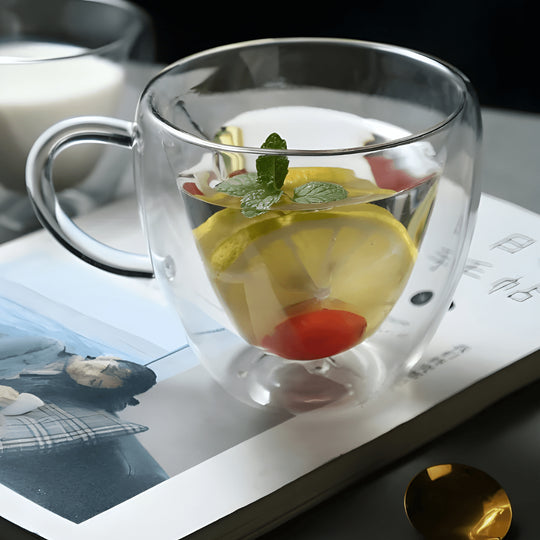Elegant double wall glass mug on marble tray with tea leaves