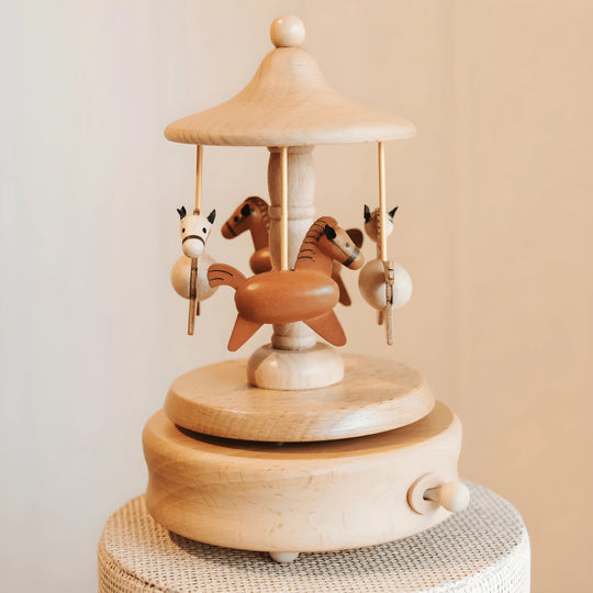 Handcrafted natural wood carousel music box with four horses on a rotating base, minimalist home decor.