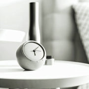 Modern grey concrete table clock displayed on a minimalist white side table