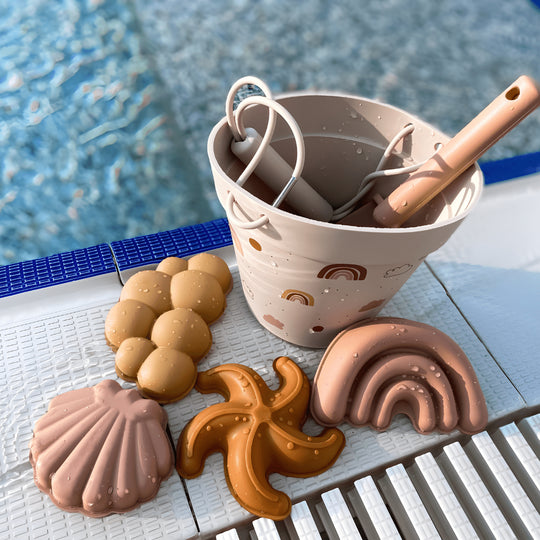 Silicone beach bucket set with shovel and sand molds for kids – BPA-free and safe, photographed on a sunny beach in Beirut, Lebanon