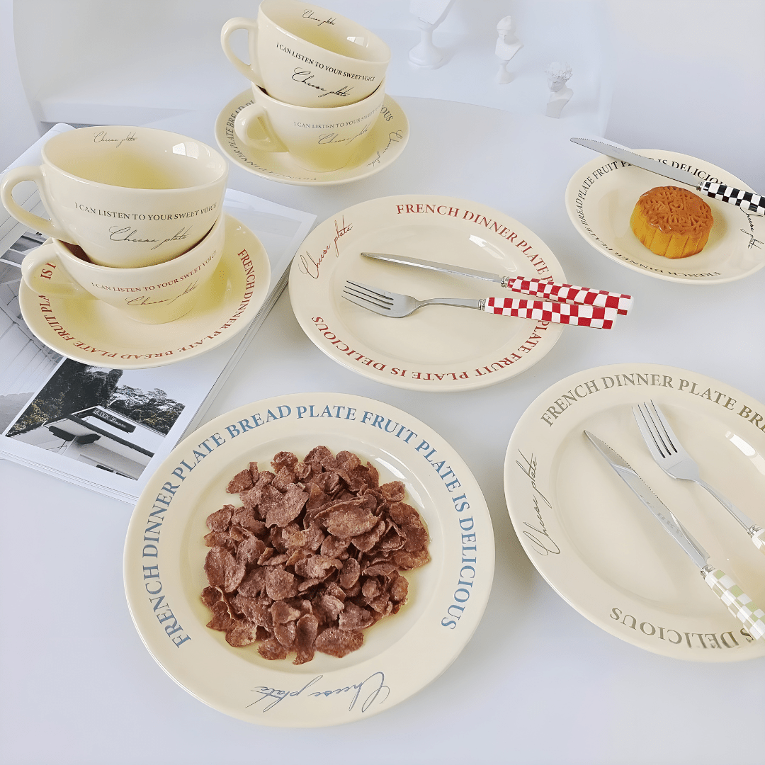 Assorted ceramic mugs and plates in cream with colorful lettering – tableware set
