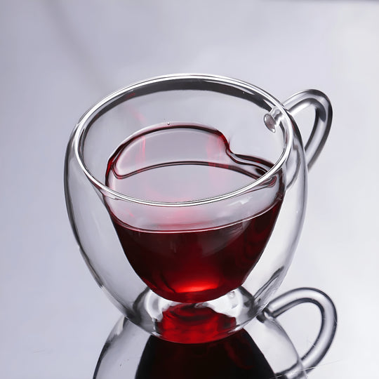 Transparent glass mug with heart-shaped inner design filled with tea