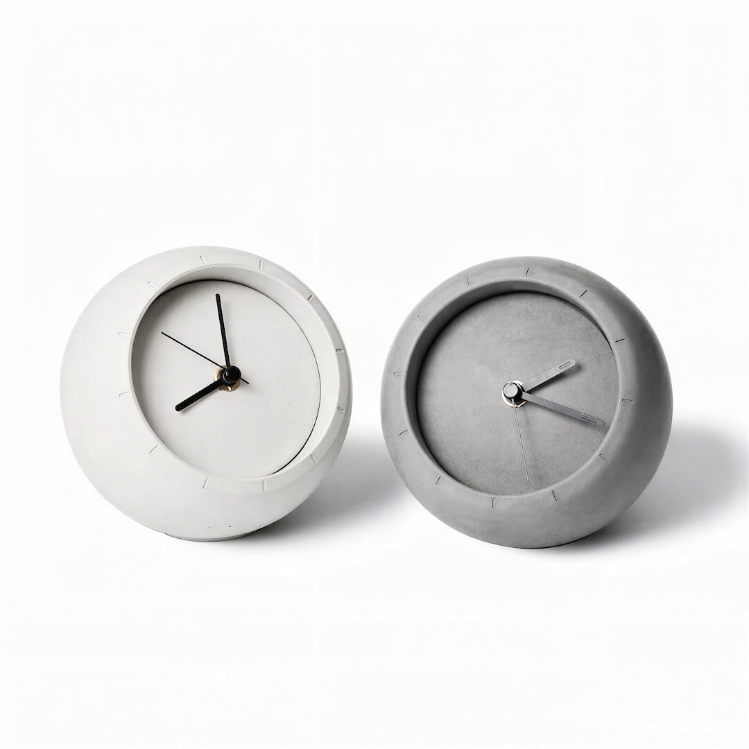 Grey and ivory sculptural concrete table clocks on a white background