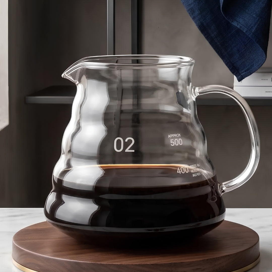 600ml clear glass coffee server without a lid, partially filled with coffee on a clean ivory background.
