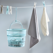 Telescopic basket with 50 clothes pegs hanging on a laundry line, practical storage for home and outdoor drying.